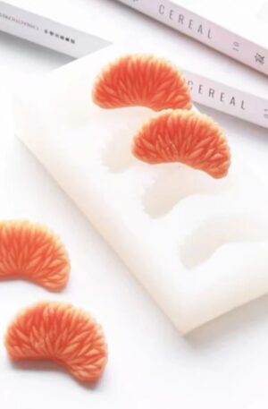 Velas artesanales con forma de gajos de naranja junto a su molde de silicón